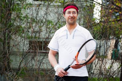 Mature man playing tennis at his backyard of his house