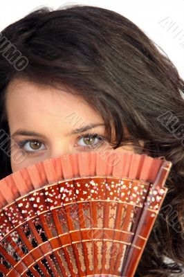 Closeup of a pretty woman hiding behind a fan Closeup of a pretty woman hiding behind a fan
