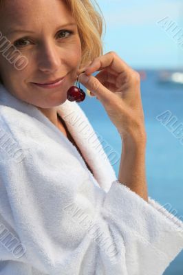 woman in front of the sea taking cherries