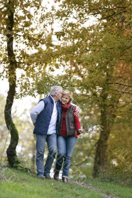 Affectionate couple strolling though park