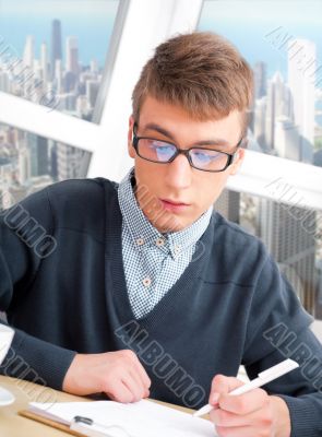 Young male student doing homework in his room at home