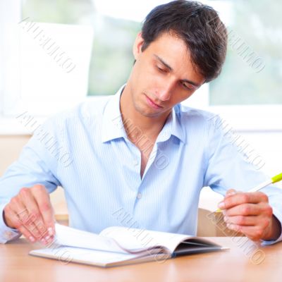 Businessman sitting indoors and writing plan in his diary