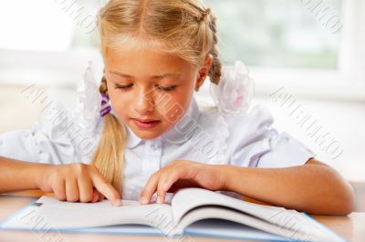 Portrait of a young girl in school at the desk.