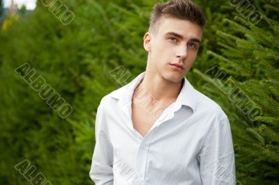 Satisfied smiling businessman standing in the green outdoors.