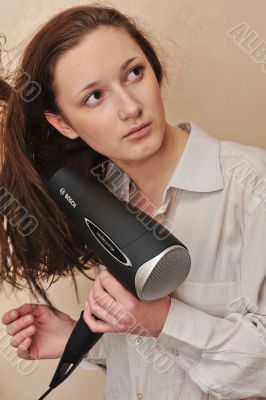 Beautiful woman drying her hair with hairdryer