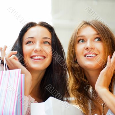 Two excited shopping woman together inside shopping mall. Horizo