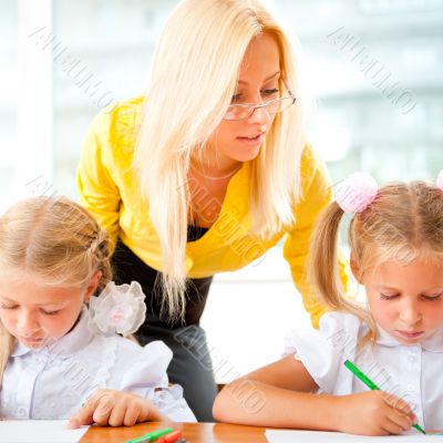 Young pretty teacher helping to her students to make exercise in