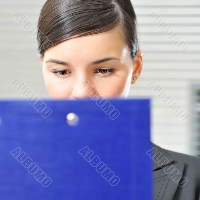 A portrait of a young business woman in an office with documents