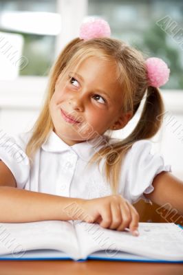 Image of smart child reading interesting book in classroom