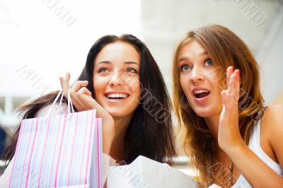 Two excited shopping woman together inside shopping mall. Horizo