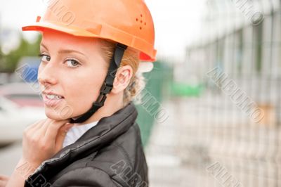 Young architect-woman wearing a protective helmet standing on th