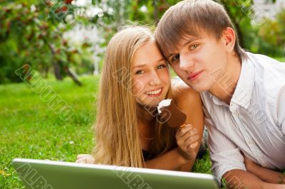 College students using laptop on campus lawn