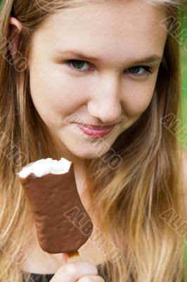 Portrait of the young beautiful smiling woman outdoors eating ic