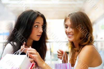 Two excited shopping woman together inside shopping mall. Horizo