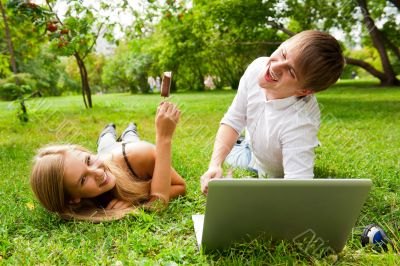 College students using laptop on campus lawn