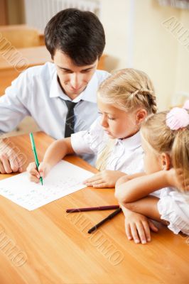 Teacher helping elementary school pupils with their tasks