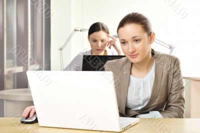 Portrait of two women working at their desks