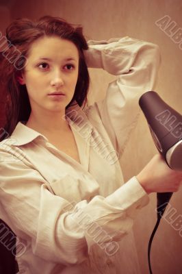 Beautiful woman drying her hair with hairdryer