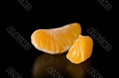 Close up photograph of a juicy Clementine orange slice on a blac