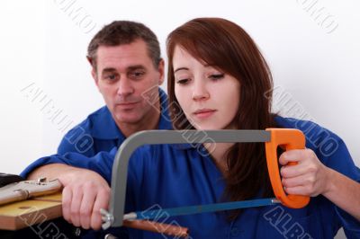 Female apprentice plumber sawing copper pipe