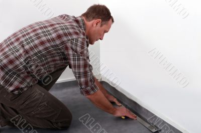 Tradesman laying down linoleum flooring