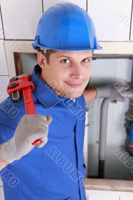 Plumber installing pipes with a large wrench