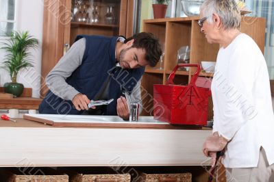 young man fixing faucet older woman