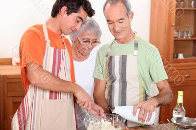 a 20 years old boy and 65 years old man and woman making cake together a 20 years old boy and 65 years old man and woman making cake together