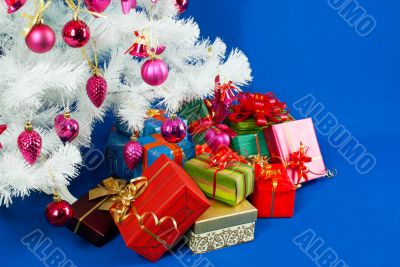 Heap of the Christmas presents under decorated white evergreen t