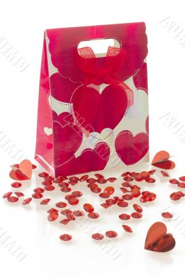 Red gift bag with heart pattern and bow, isolated on white background