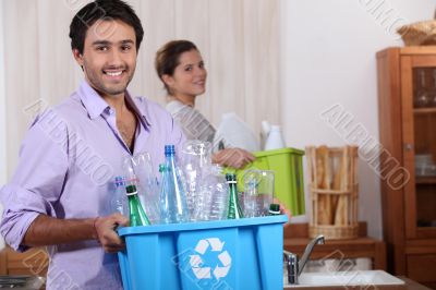 a young couple recycling plastic in their kitchen a young couple recycling plastic in their kitchen