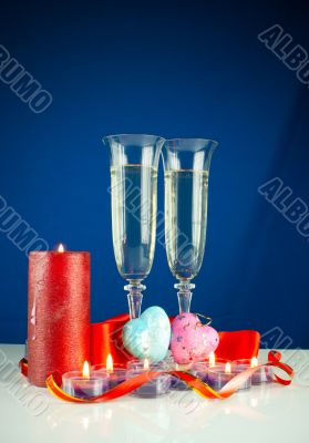 Two wineglasses and burning candles against blue background