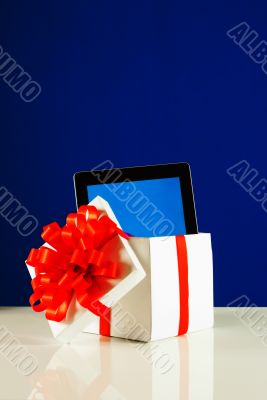 Tablet PC in a gift box against blue background