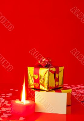Presents and burning heart shaped candle with blank card