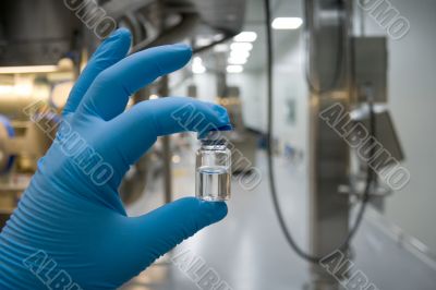 Hand in rubber glove holding a bottle of medicine