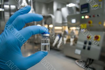 Hand in rubber glove holding a bottle of medicine