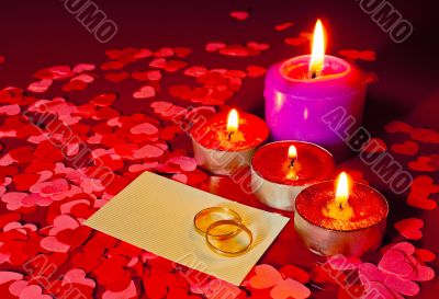 Two rings and a card with marriage proposal with four candles