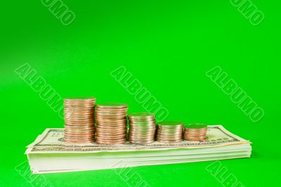 Coins stacked in bars laying on stack of 100 dollar bills