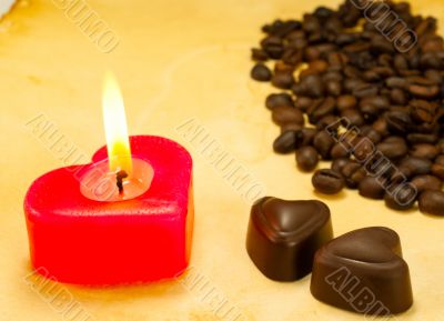 Burning candle, two heart shaped candies and cofee beans