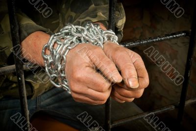 Hands of man tied up with chain