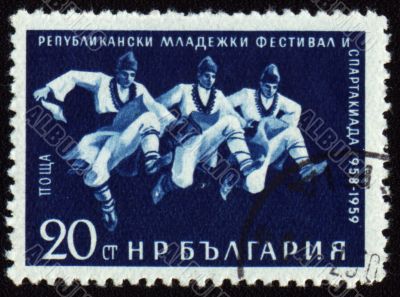 Three dancing men in Bulgarian national costumes on post stamp