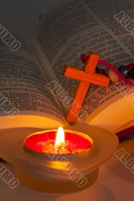 Open Bible with cross and burning candles