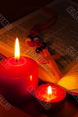 Open Bible with cross and burning candles
