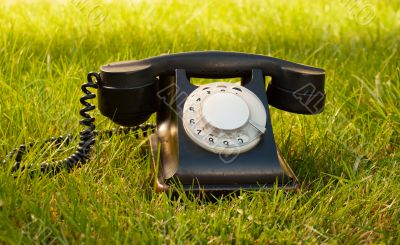 Retro styled rotary telephone on grass Retro styled rotary telephone on grass