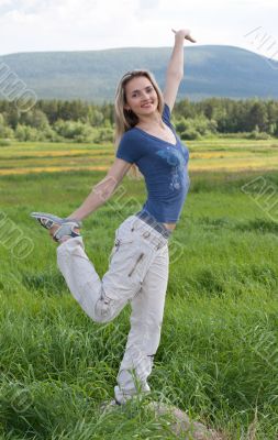 Beautiful girl stand on one leg in green field