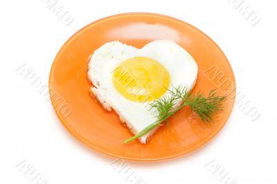 Fried egg in form heart on plate with dill
