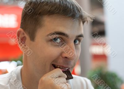 Young man eats chocolate