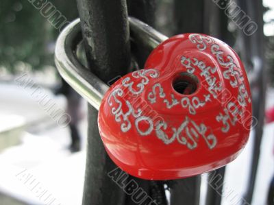 Locked wedding padlock on the handle of the bridge Locked wedding padlock on the handle of the bridge