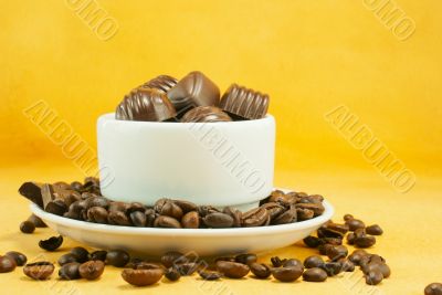 Cup full with coffee beans and chocolate candies Cup full with coffee beans and chocolate candies