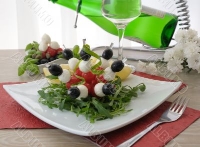 Appetizer of mozzarella, cherry tomatoes and olives with Arugula